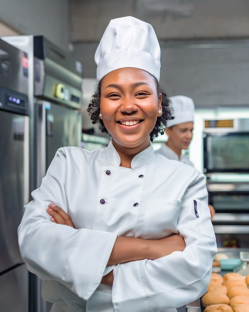 a chef smiles, arms folded, in a kitchen